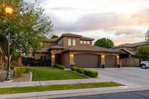 Stucco exterior residence featuring a stone facade entry, a three-car garage, mature landscaping, and an arched entry