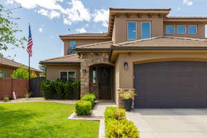 Stucco and stone exterior featuring an arched entryway, tile roof, and an integrated two-car garage