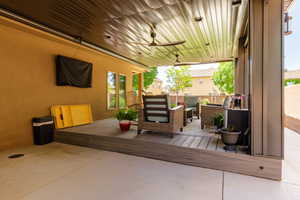 Expansive covered patio featuring a wood-finish deck, multiple ceiling fans, recessed lighting, and a stucco exterior wall