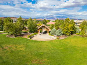 Expansive green lawn with a tiered stone amphitheater leading to a large gazebo featuring a wood beam structure and a shingled roof