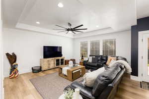 Spacious living area featuring a tray ceiling with recessed lighting and a ceiling fan