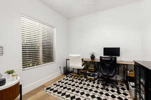 Bright room with wood-finish flooring, crisp white walls, and a large window with horizontal blinds