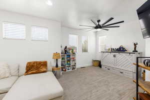 Carpeted room featuring a ceiling fan with integrated lighting, multiple windows with blinds, and white walls