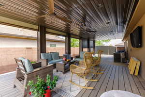 Covered outdoor patio featuring wood-look plank flooring, a slatted ceiling with two ceiling fans, and recessed lighting