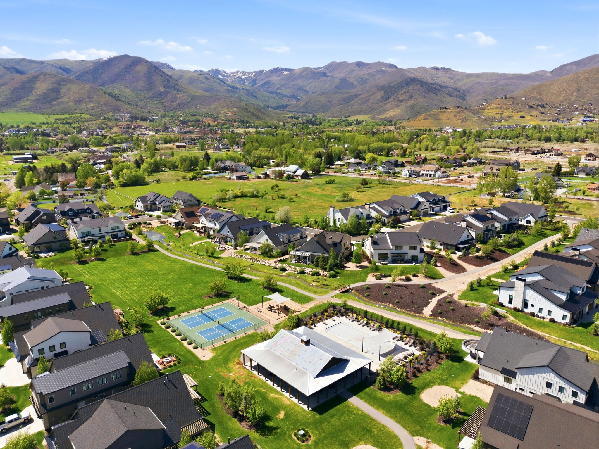 Aerial perspective showcasing a residential community with contemporary homes, surrounded by green spaces and distant mountains