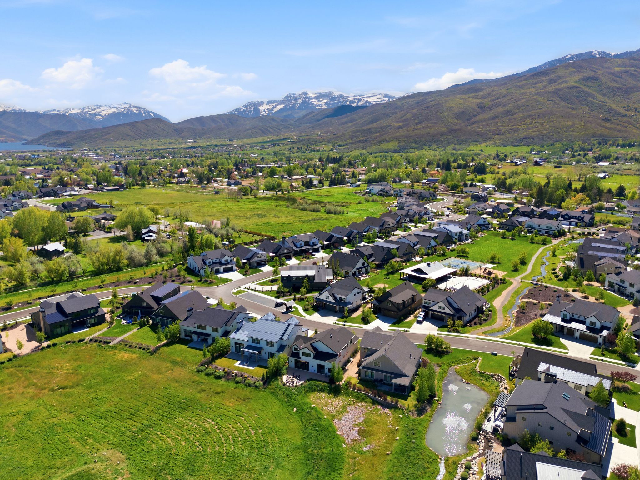 Aerial perspective showcasing a residential community nestled against a backdrop of mountains and a distant body of water