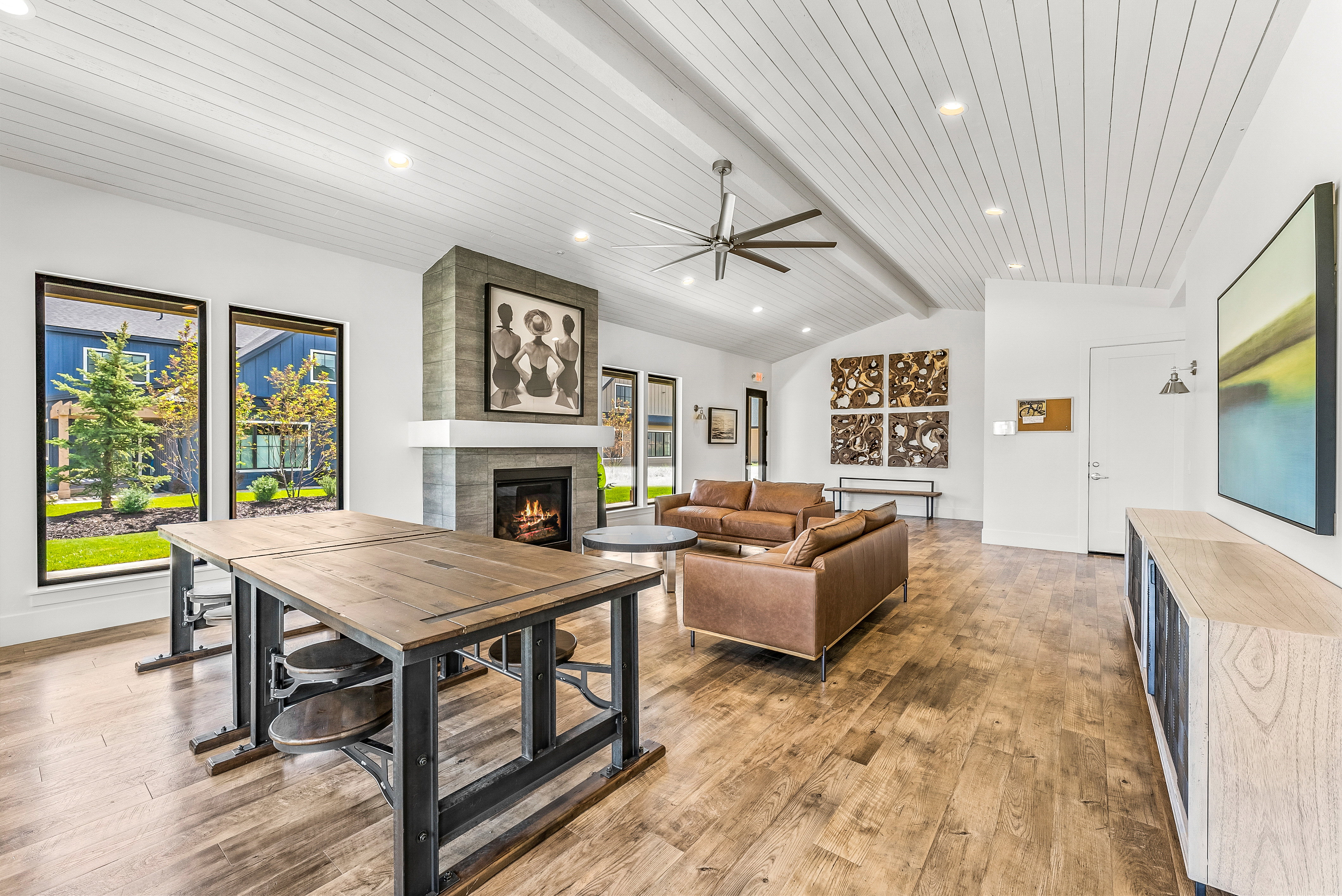 Spacious common area featuring a vaulted ceiling with white planking, recessed lighting, and a prominent fireplace with a substantial mantel