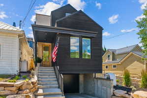 Contemporary black horizontal siding exterior with a light wood entry door and a covered porch