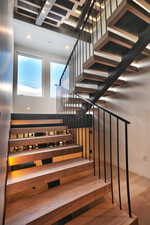 Modern open-riser staircase featuring wood-finish treads and risers with integrated lighting
