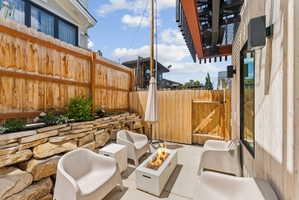 Private patio space featuring a built-in fire pit, stone retaining wall with plantings, and a wooden privacy fence