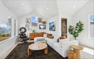 Bright living area featuring vaulted ceilings with recessed lighting, light wood-finish flooring, and multiple windows