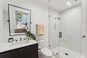 Modern bathroom featuring a frameless glass shower enclosure with matte black hardware and white grid-patterned wall tiles