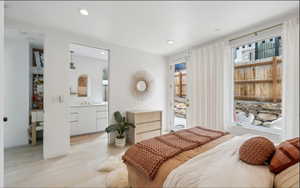 Bedroom with light wood-finish flooring, recessed lighting, and a glass-paned door leading to an outdoor area