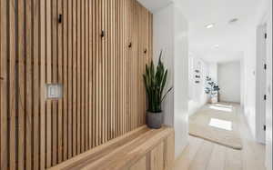 Entryway featuring a wood-slat accent wall with integrated coat hooks, a built-in wood bench, and light wood-finish flooring
