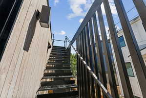 Exterior metal staircase with black balusters and treads, leading to an upper level