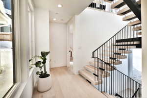 Modern open-tread staircase with black metal railings and light wood-finish treads
