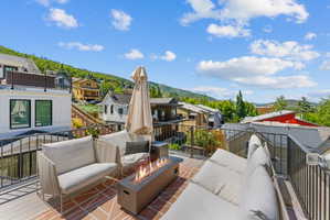 Rooftop deck featuring a built-in fire pit, metal railings, and a combination of wood-finish and patterned brick-style flooring