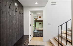 Entryway featuring a dark wood-paneled accent wall with integrated coat hooks and a built-in bench