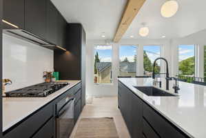Contemporary kitchen featuring a gas range, built-in oven, and under-cabinet lighting