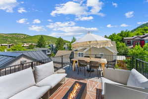 Rooftop deck featuring a built-in fire pit, metal railings, and a composite decking surface