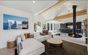 Living area featuring a vaulted ceiling with exposed wood beams, recessed lighting, and light wood-finish flooring