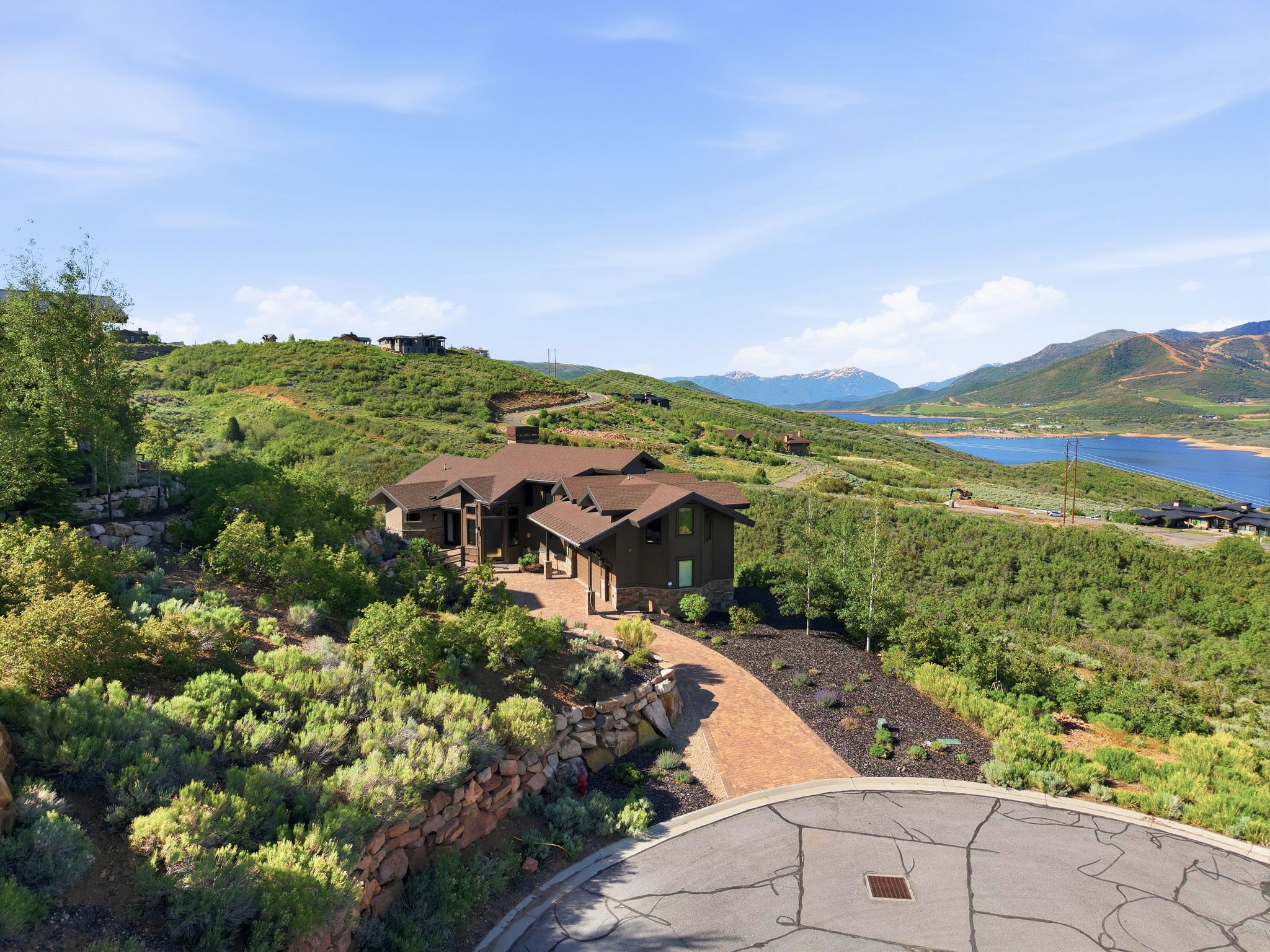 Hillside residence featuring a multi-level design, a paved driveway, and a natural stone retaining wall