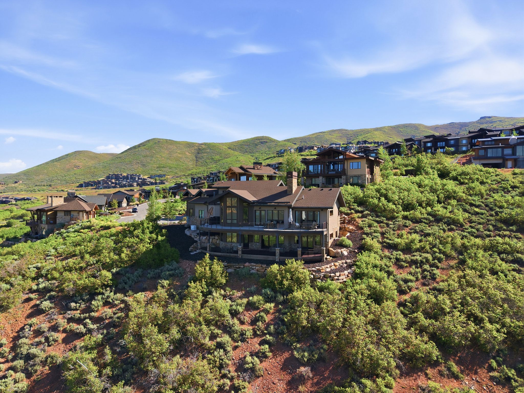 Multi-level residence featuring a stone and stucco exterior, multiple outdoor terraces, large windows, and a dark shingled roof