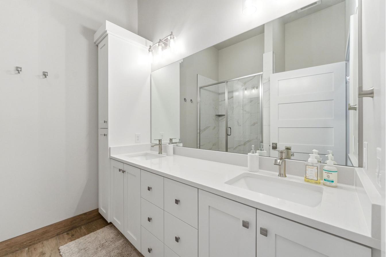 Bathroom featuring a dual vanity with white cabinetry, integrated sinks, and brushed nickel hardware
