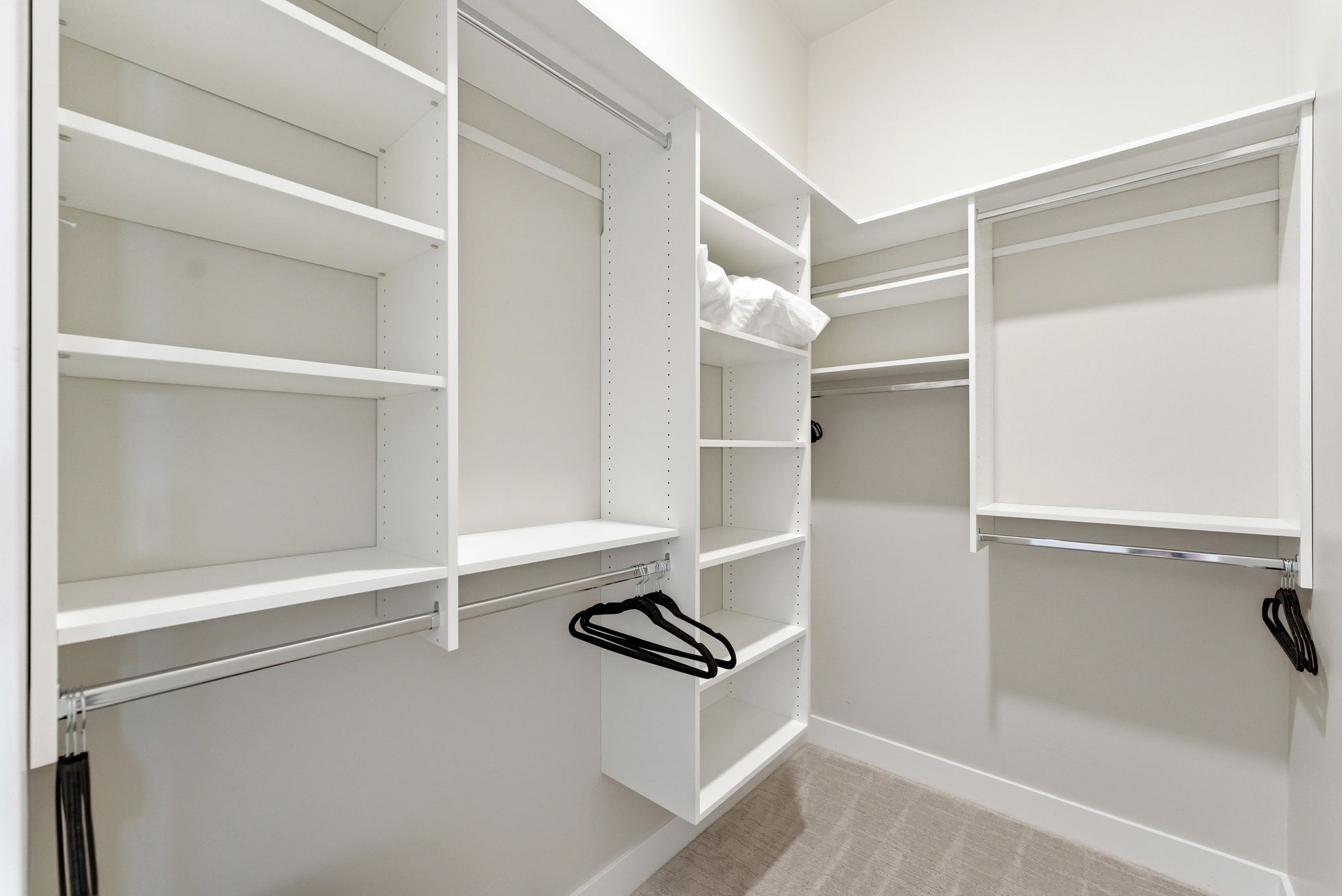 Custom closet system featuring white shelving and chrome hanging rods