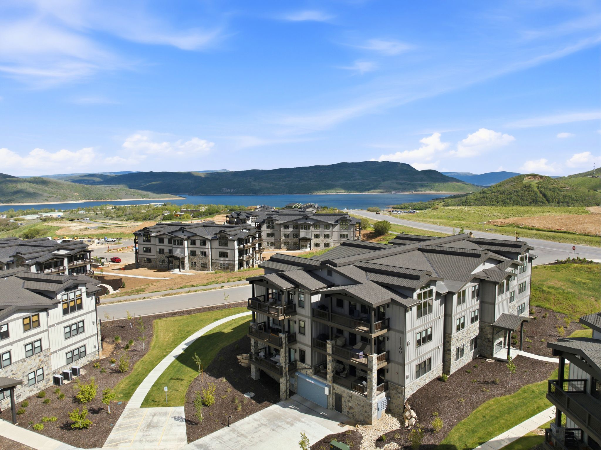 Modern multi-story buildings featuring stone and siding exteriors, private balconies, and dark-pitched roofs
