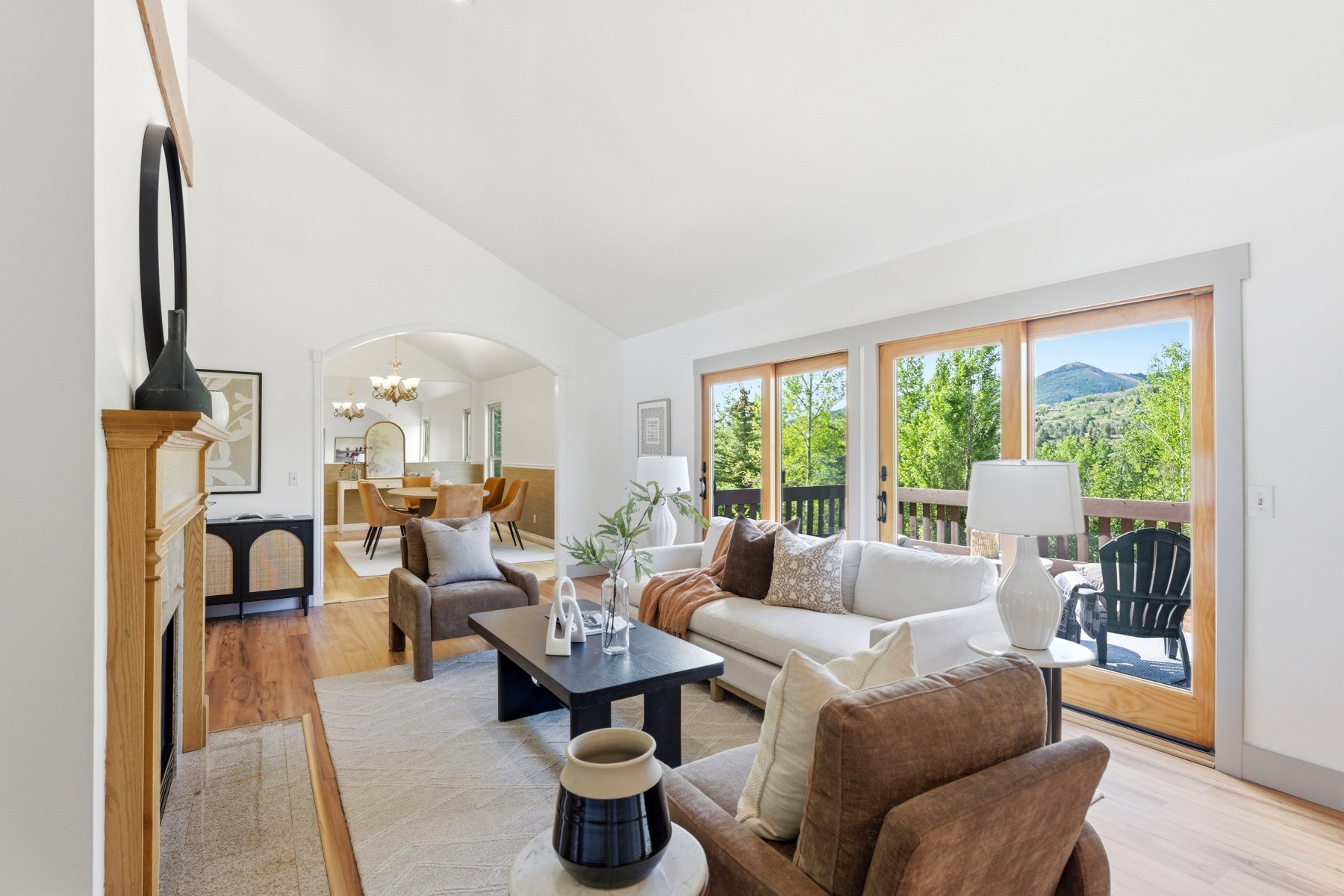 Living area featuring a vaulted ceiling, wood-finish flooring, and a decorative fireplace with a wood mantle