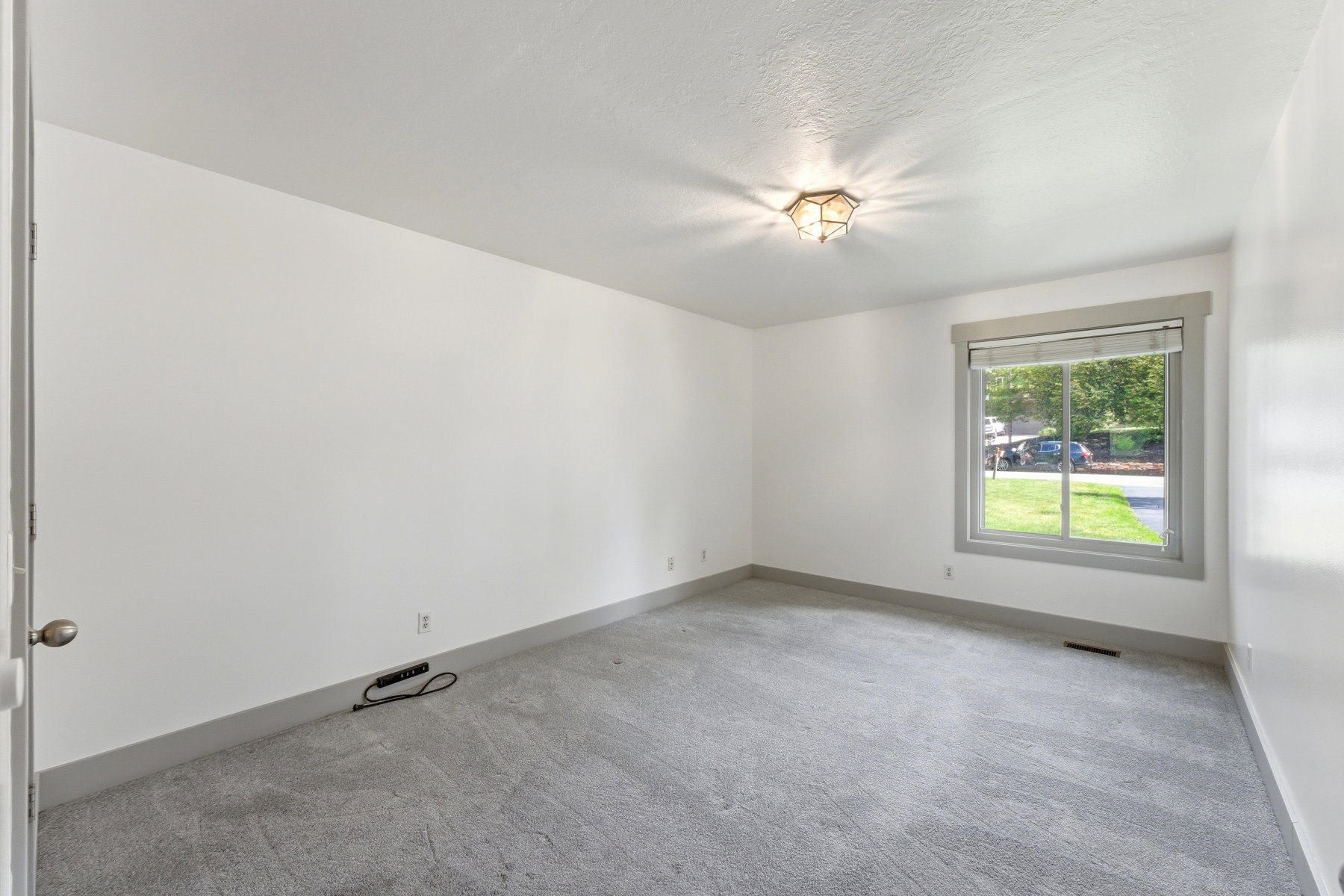 Spacious room featuring light gray carpeting and white painted walls