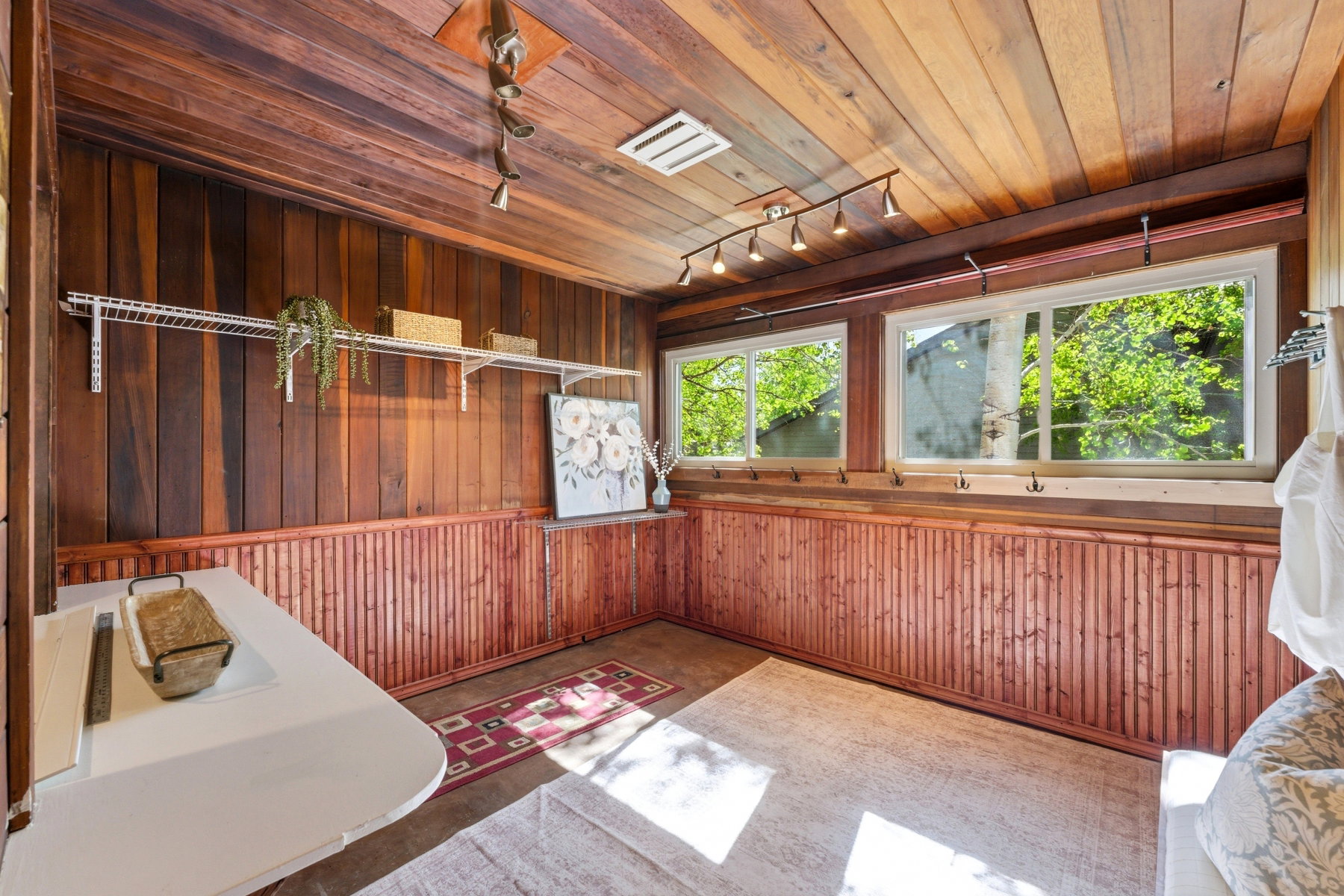 Wood-paneled room featuring a slatted wood ceiling, track lighting, and two sliding windows