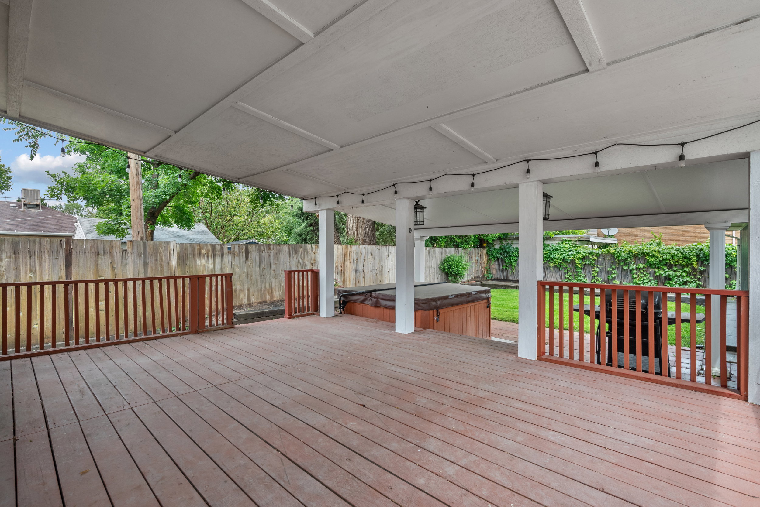 Expansive covered deck featuring wood-finish flooring, white support columns, and perimeter railing