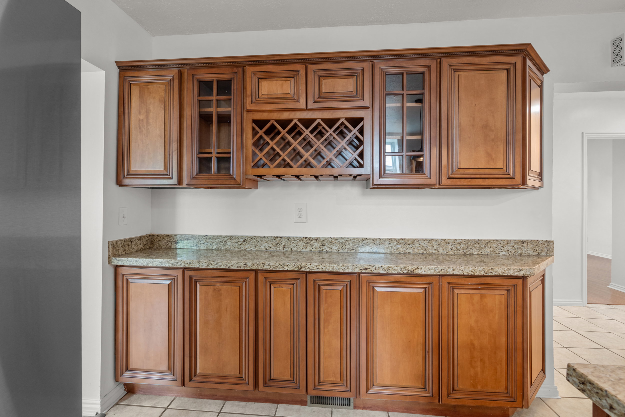Built-in cabinetry with wood-finish doors, glass-front upper cabinets, and an integrated wine rack