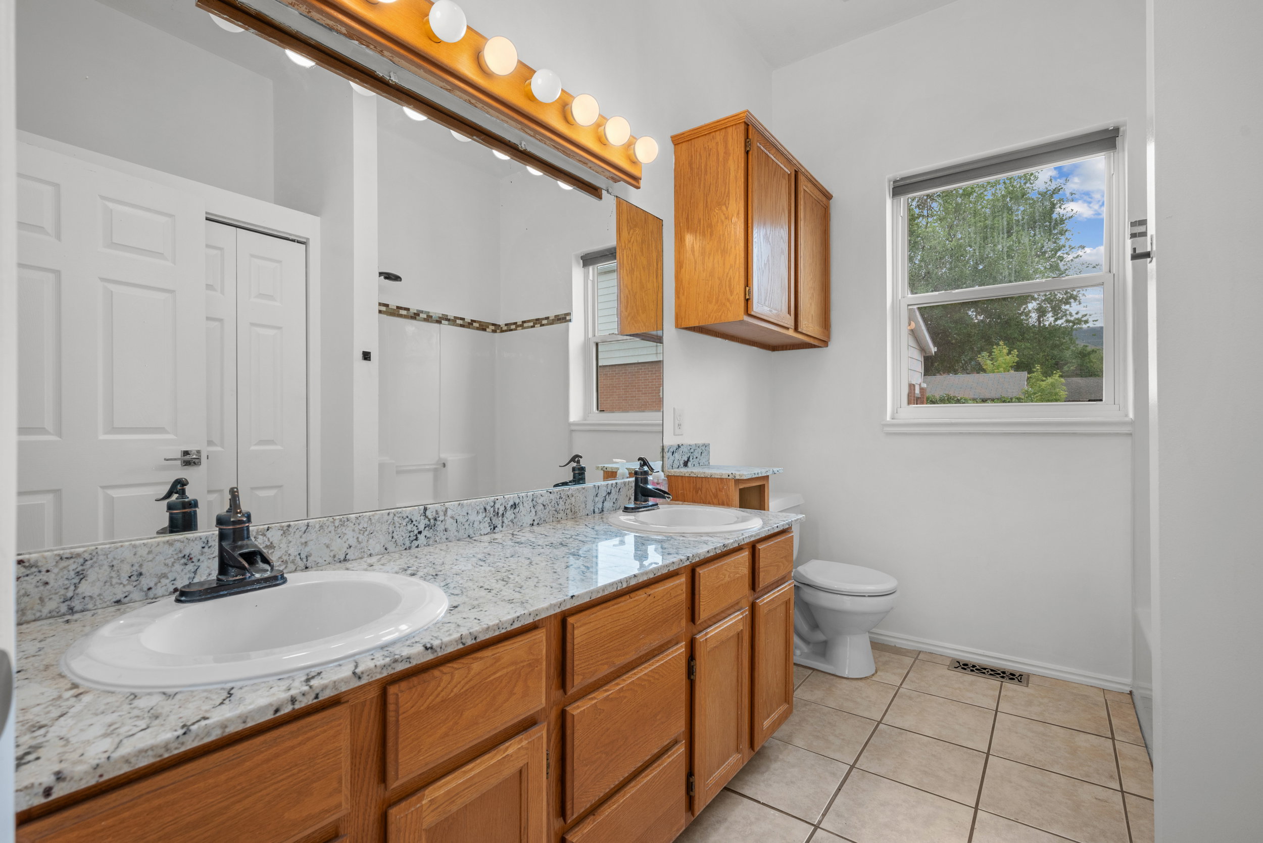Bathroom featuring a dual vanity with granite-style countertops and wood cabinetry