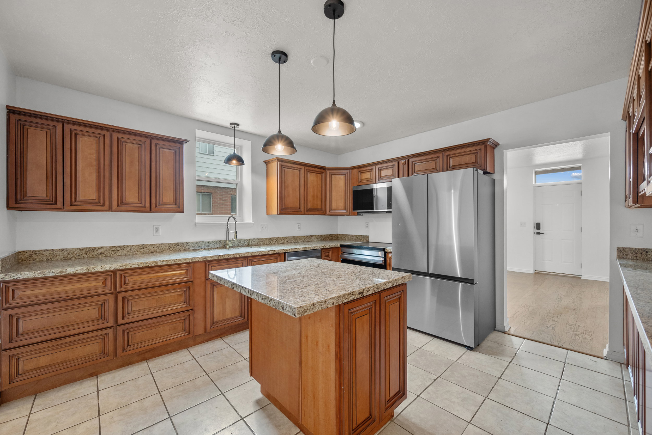 Kitchen featuring a center island, wood-finish cabinetry, stone countertops, and tile flooring