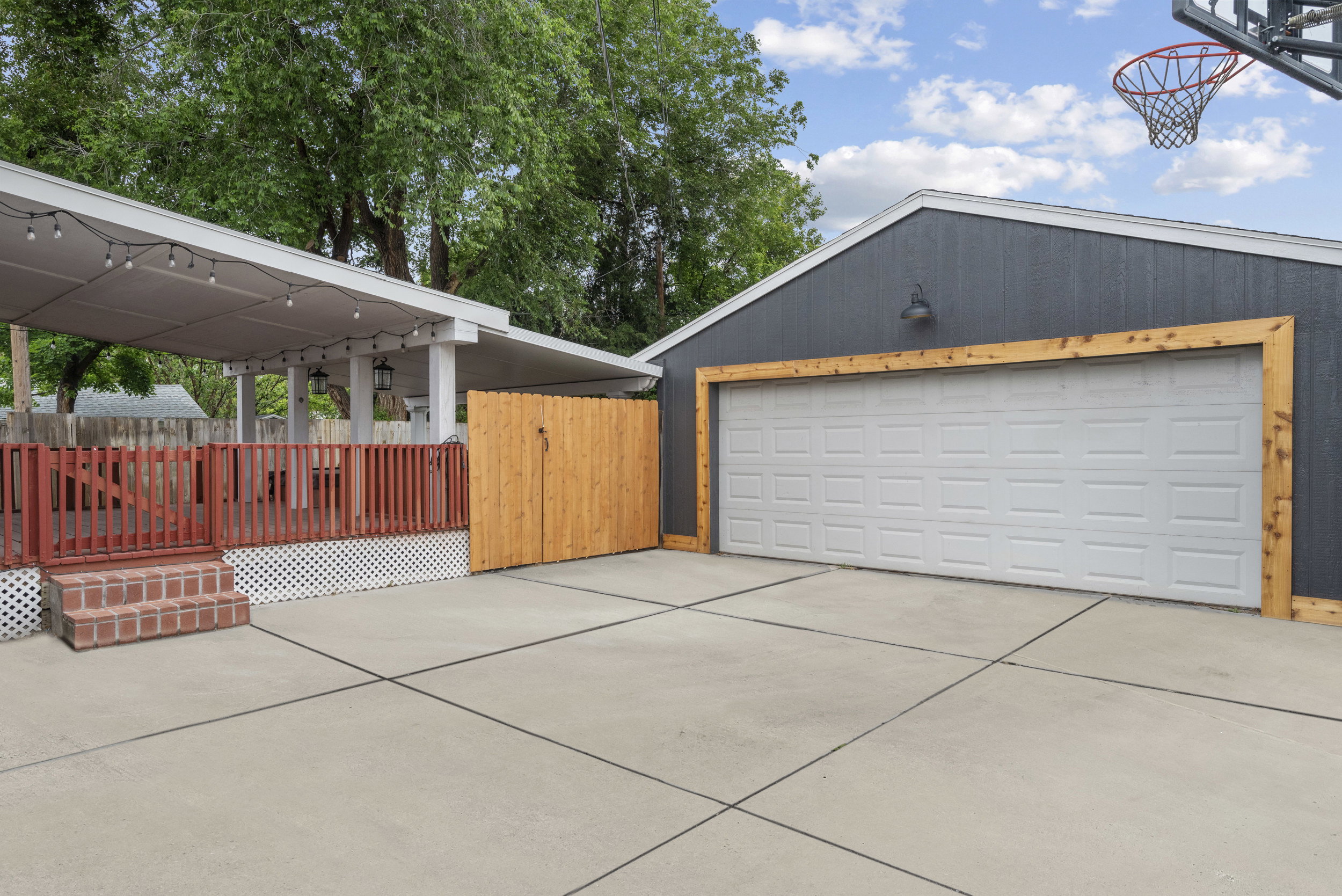 Spacious concrete driveway featuring a detached garage with wood-trimmed entry