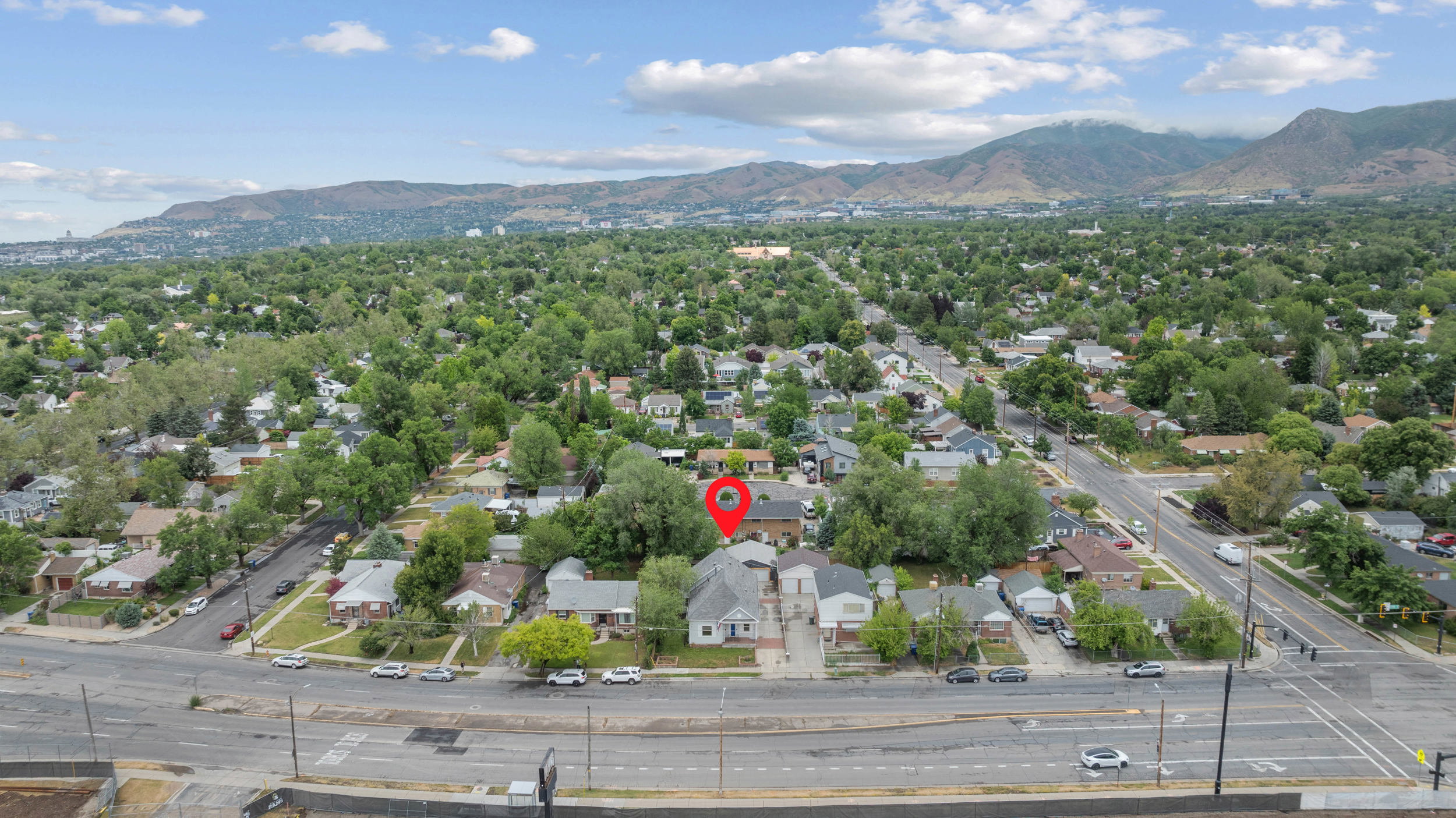 Aerial perspective showcasing a residential neighborhood with mature trees and a distant mountain range