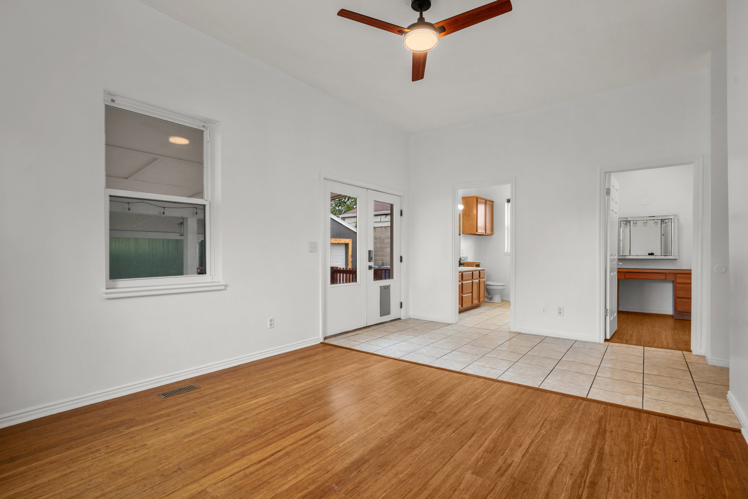 Open-concept room featuring wood-finish flooring, white walls, and a ceiling fan with integrated lighting