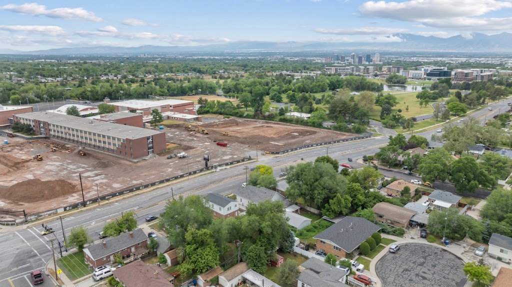 Aerial perspective showcasing a broad urban landscape with residential properties, commercial structures, and extensive green spaces