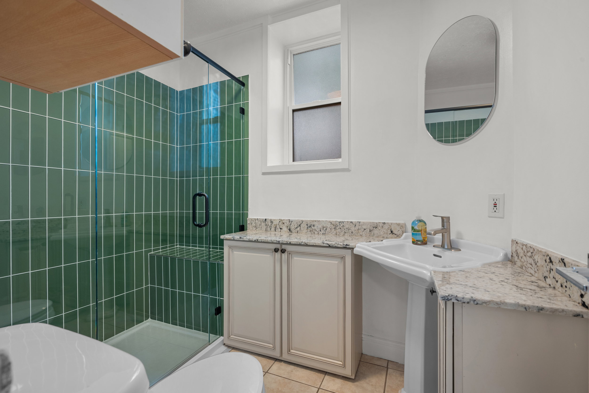 Modern bathroom featuring a walk-in shower with green subway tile surround and a built-in bench