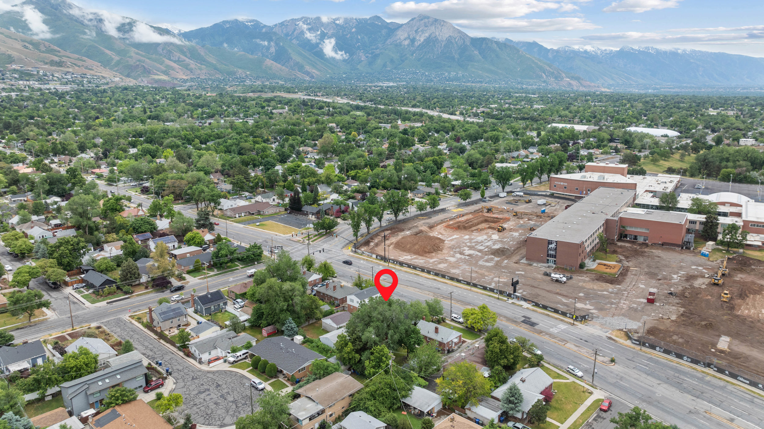 Aerial perspective showcasing a residential area with established homes, mature trees, and a mountain backdrop