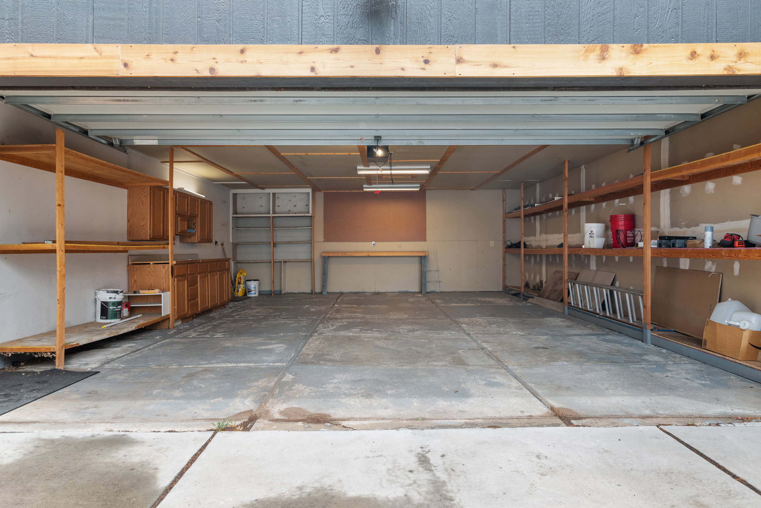 Spacious garage featuring concrete flooring and exposed ceiling beams