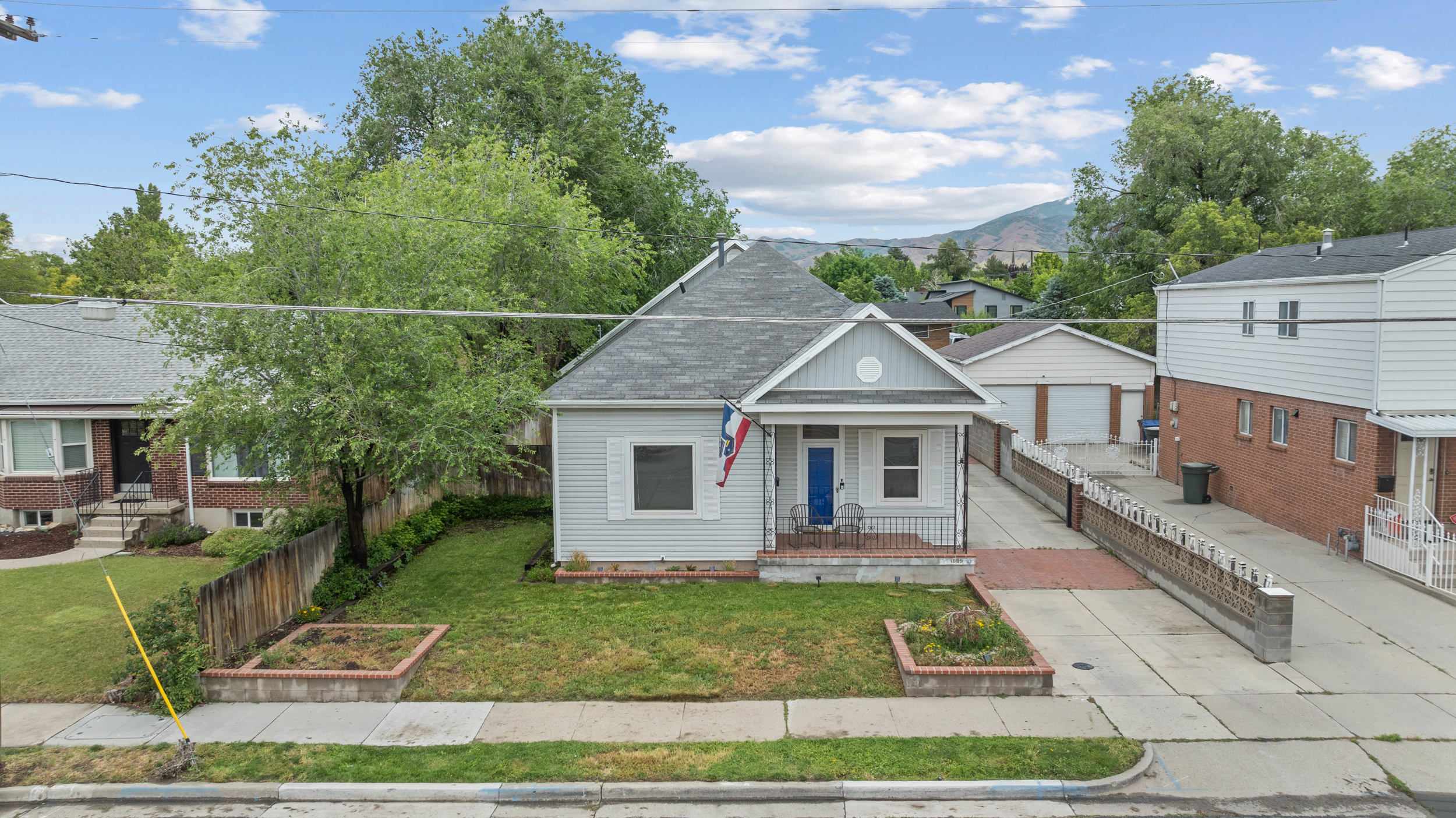 Charming single-story residence with light gray siding and a prominent blue entry door