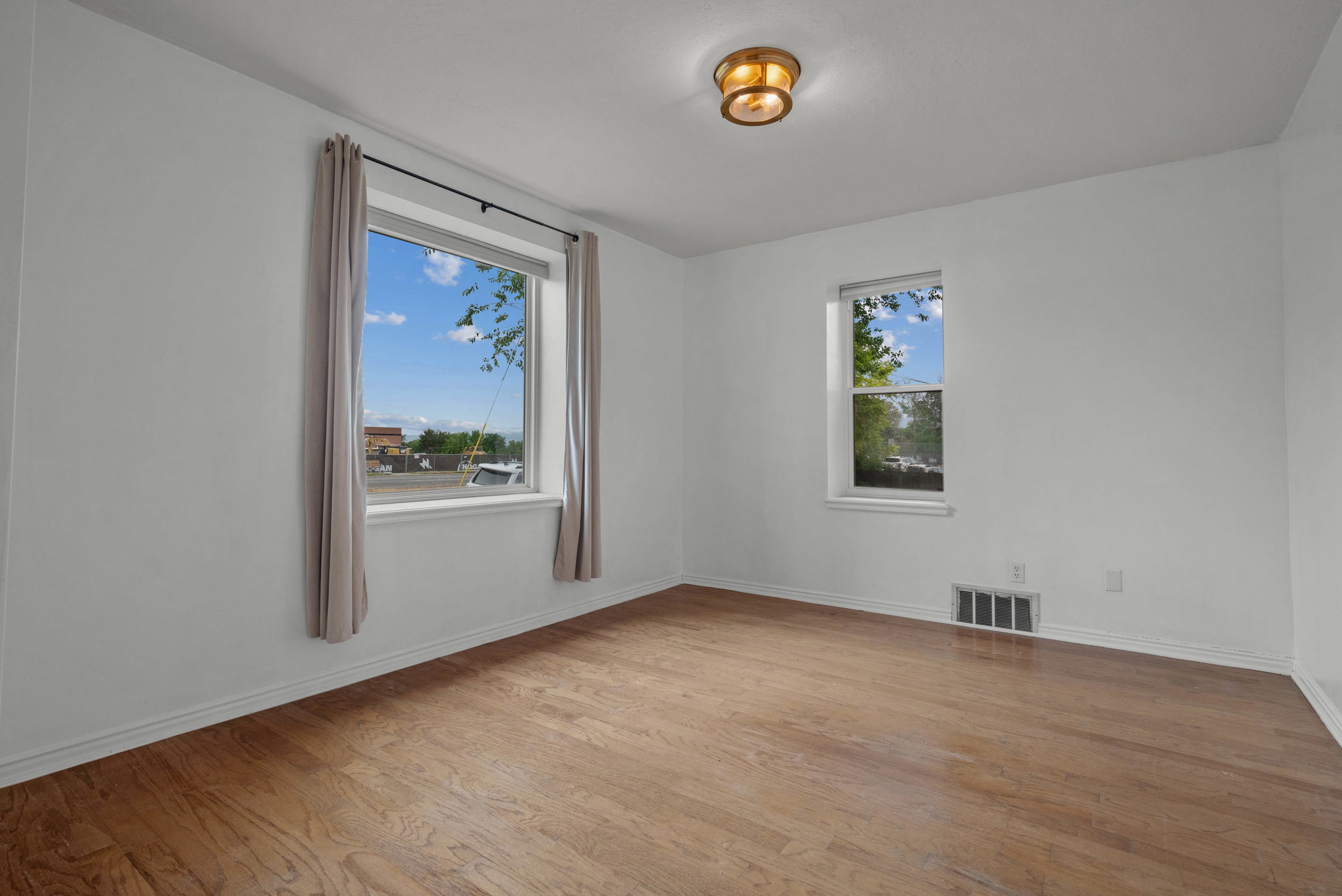 Bright room featuring wood-finish flooring, white baseboards, and a semi-flush mount ceiling fixture