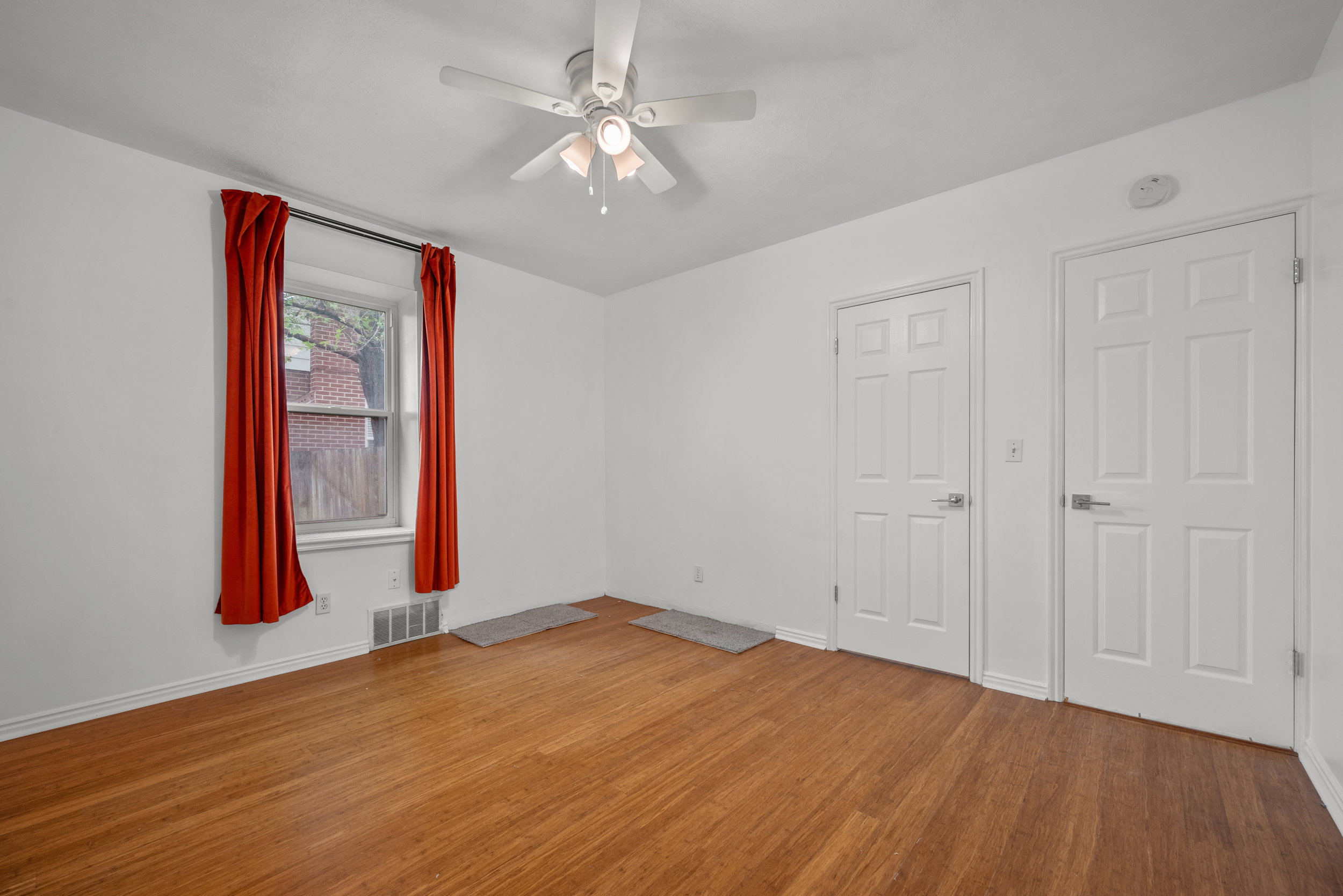 Room featuring wood-finish flooring, two paneled doors, and a window with a sill