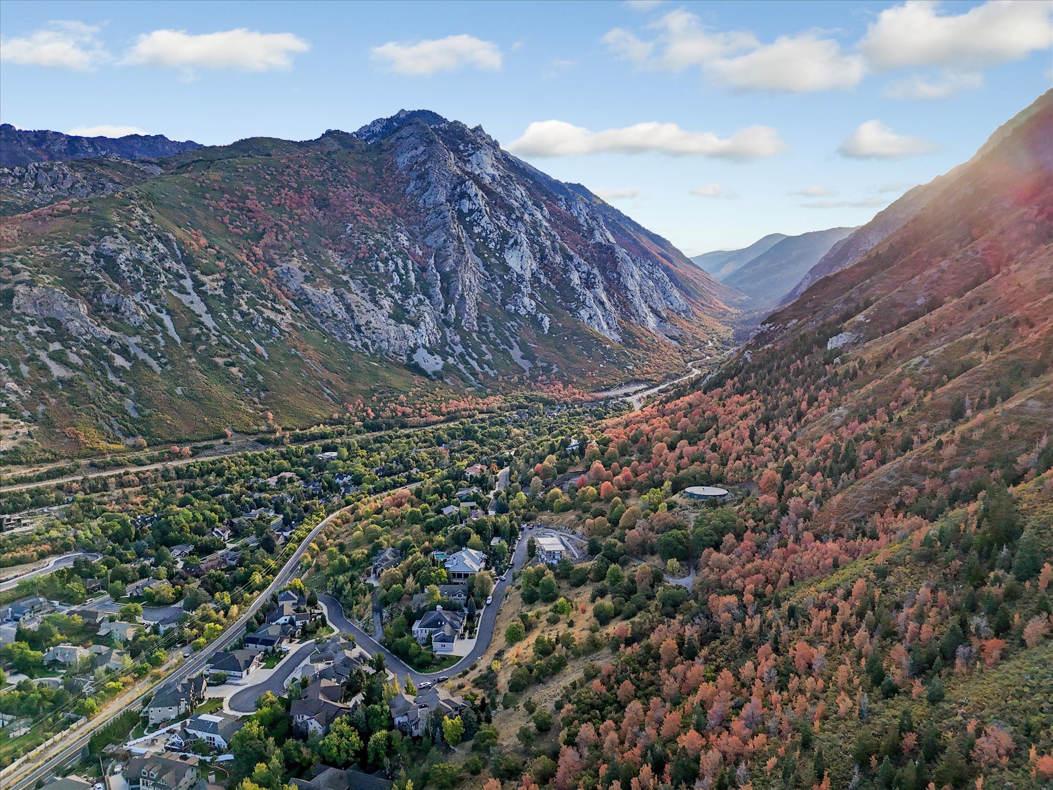 Mountainous terrain with varied foliage, featuring a residential community with winding roads and scattered structures