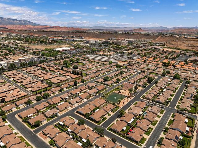 Expansive residential development featuring numerous homes with brown-tiled roofs, a central pond feature, and paved roadways