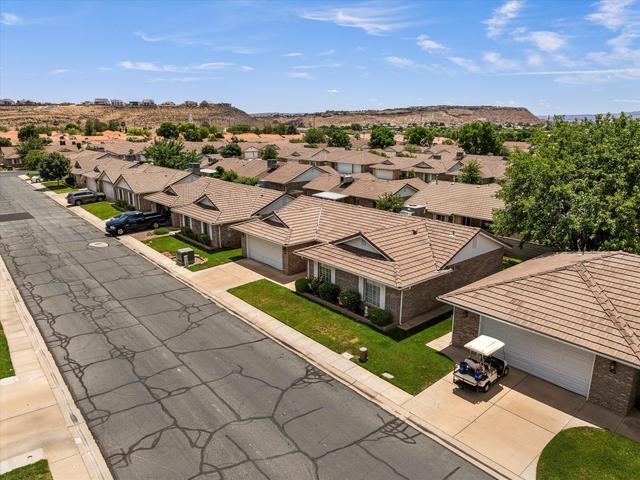 Residential street with single-story homes featuring brick exteriors, pitched tile roofs, and attached garages